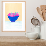 A framed original gouache painting featuring a blue bowl of pink tomatoes on a light yellow background, styled on a wooden shelf next to white ceramic kitchen items including a cup, pitcher, and wooden utensils.