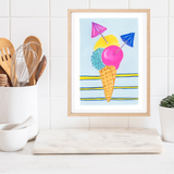 A framed original gouache artwork featuring a colourful ice cream cone illustration with three scoops and two small umbrellas, displayed on a marble cutting board in a kitchen setting.
